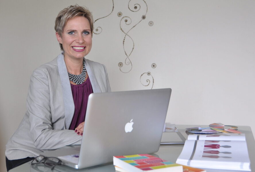 Susanne Voggenberger am Schreibtisch mit Arbeitsmaterialien und Laptop zur Stilberatung und für Online Personal Shopping